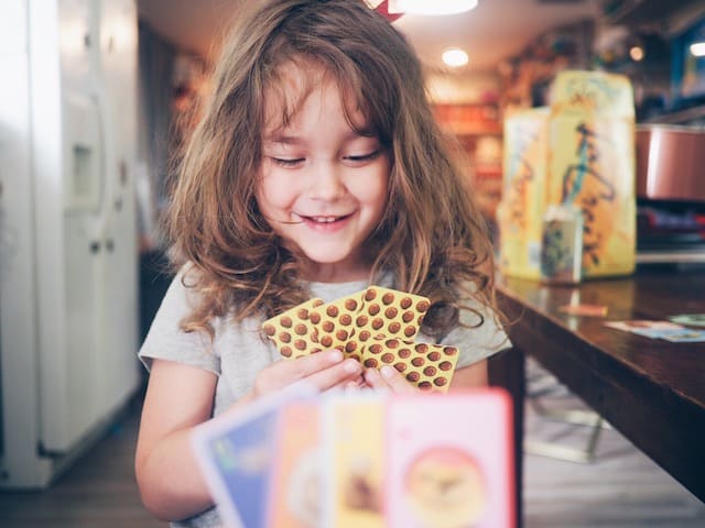 Young child playing one of the best board games for kindergartners: Sleeping Queens